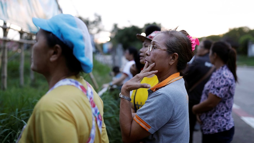 Nervous onlookers watch on for news at Thai cave