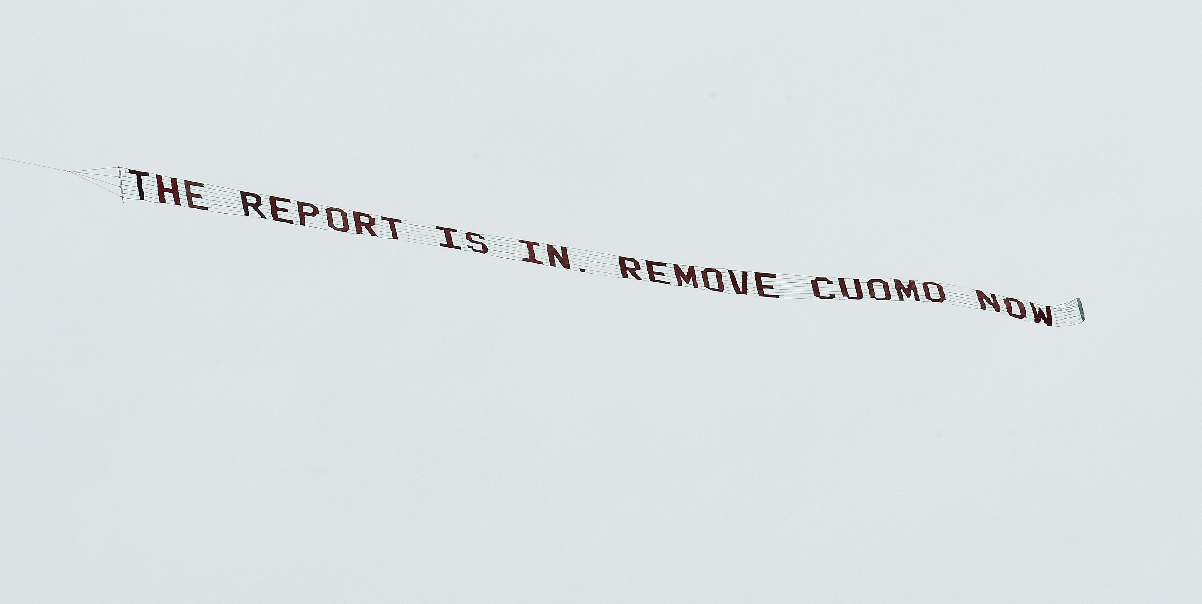 A banner flying behind a plane reads: "The report is in. Remove Cuomo now"