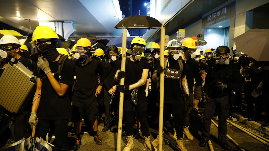 Protesters prepare to confront riot police in Hong Kong, they are wearing gas masks, black clothing and hard hats.