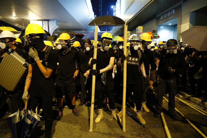 Protesters prepare to confront riot police in Hong Kong, they are wearing gas masks, black clothing and hard hats.