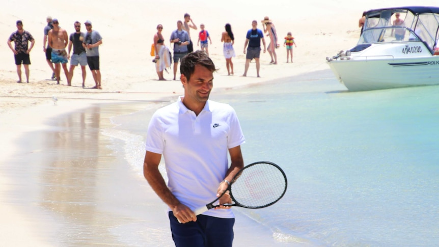 Roger Federer walking along the beach holding a tennis racquet on Rottnest Island