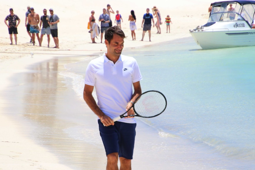 Roger Federer walking along the beach holding a tennis racquet on Rottnest Island