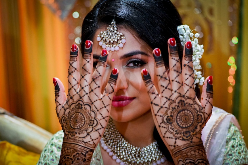 A woman in traditional Indian dress shows the henna work on her hands.