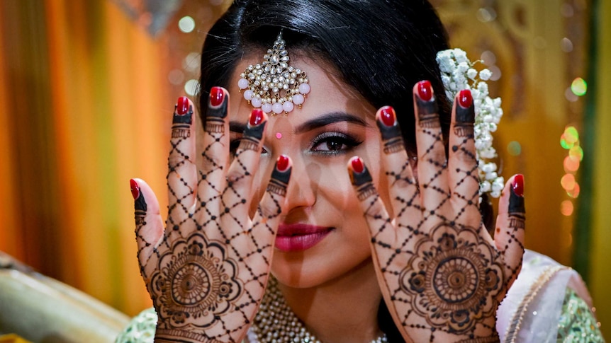 A woman in traditional Indian dress shows the henna work on her hands.