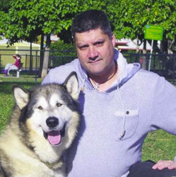 A man in a grey hoodie with a husky.