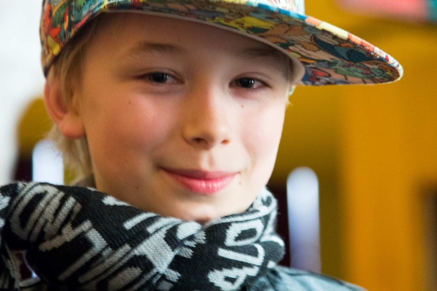 A boy in a colourful baseball cap looks at the camera.