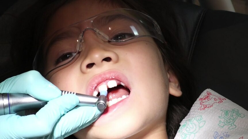 Girl sitting in dentist's chair getting her teeth cleaned