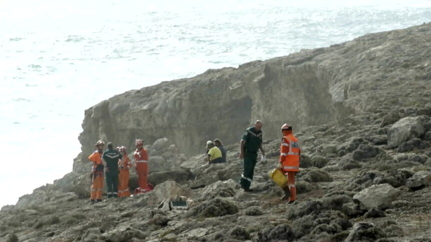 SES and paramedics on a rocky shore with waves behind