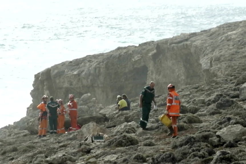 SES and paramedics on a rocky shore with waves behind