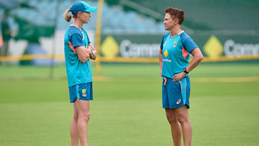 Meg Lanning and Shelley Nitschke stand about a metre apart facing each other on a grassed oval.