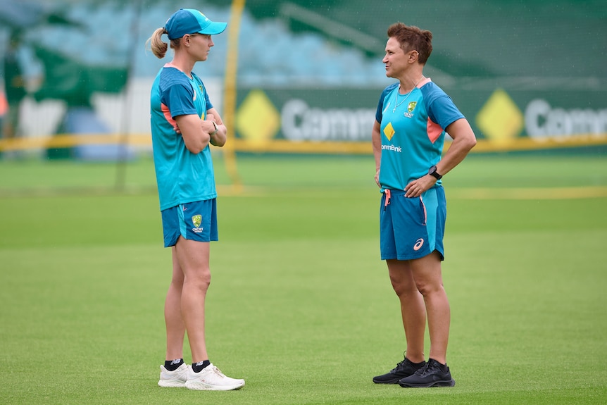 Meg Lanning and Shelley Nitschke stand about a metre apart facing each other on a grassed oval.