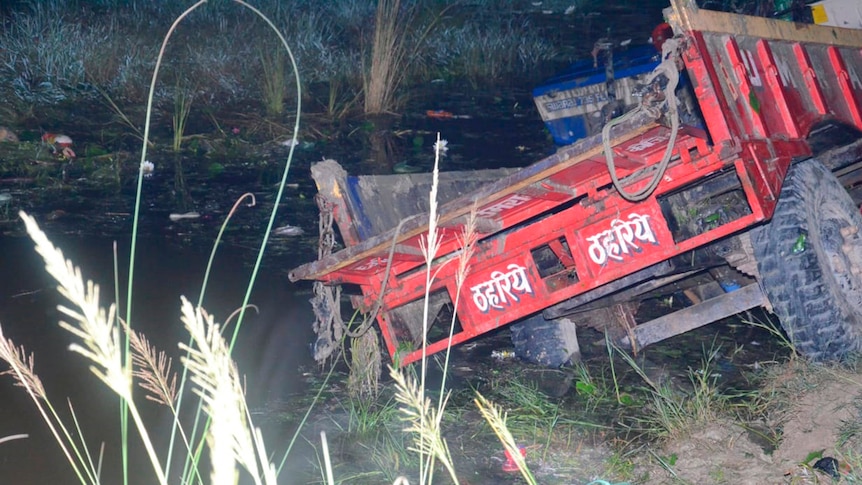 Rear view of red farm tractor inside a pond at night.
