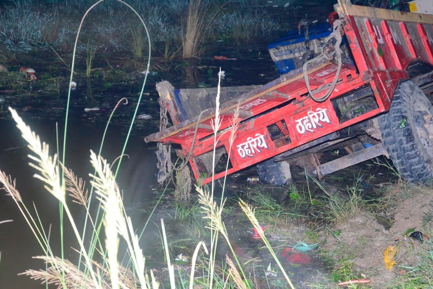 Rear view of red farm tractor inside a pond at night.