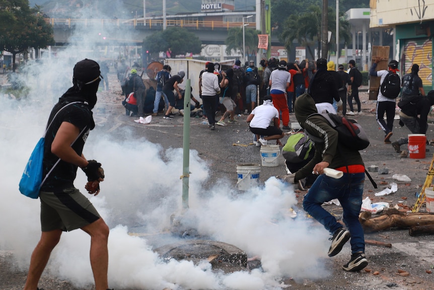 Men run through tear gas.