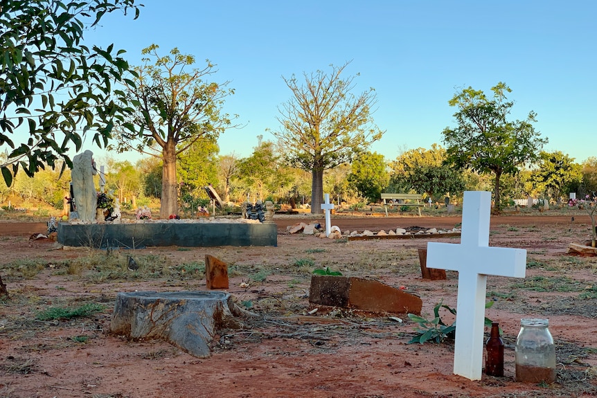 A bush cemetery with boab trees in the background and gravestones in the foreground.