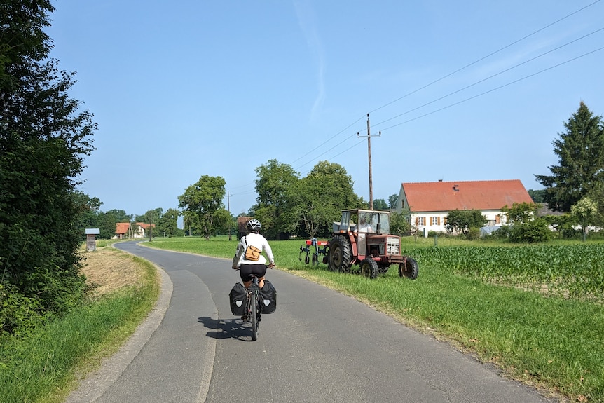 A bicycle rider rides their bike down a bicyle path in the European countryside.