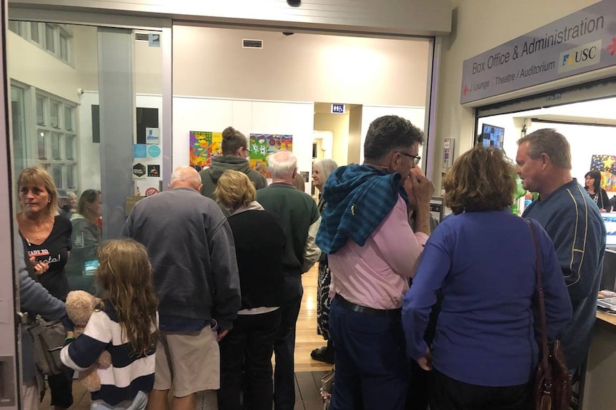 A group of people standing at the door of a public building.