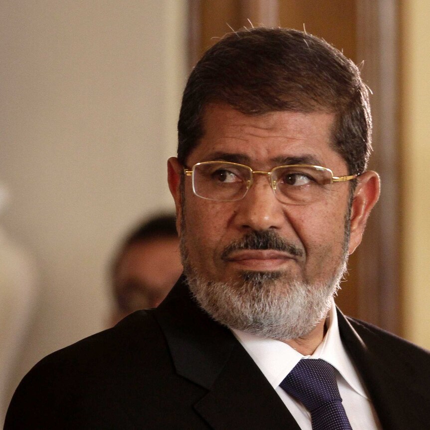 Egyptian President Mohammed Morsi wears glasses and looks over his shoulder