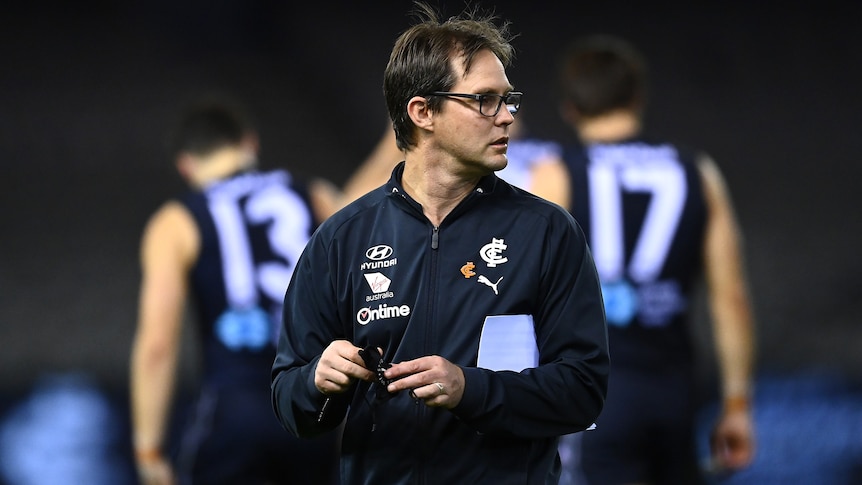 AFL coach standing in the middle of the field after a match