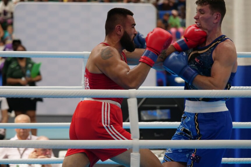 A man wearing red punches a man wearing blue in the face.
