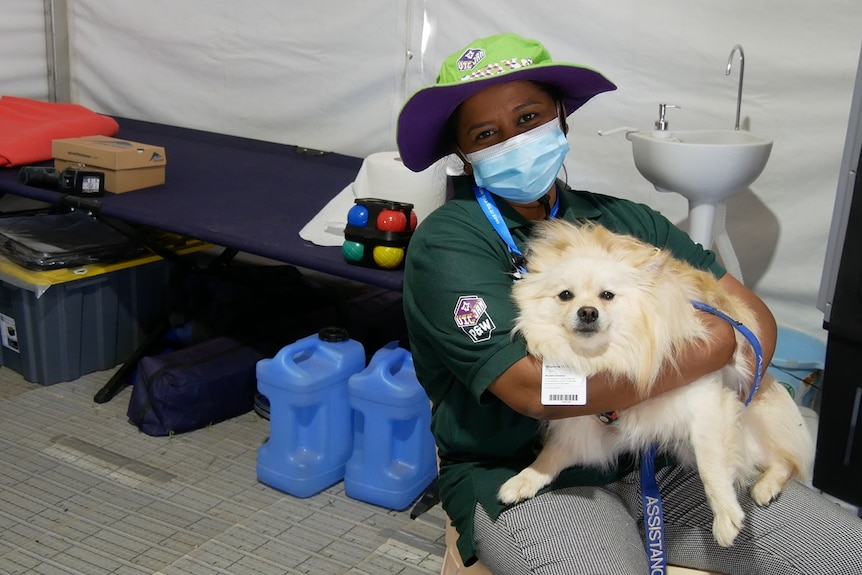 Dog sitting on a woman's lap and smiling in a first aid room