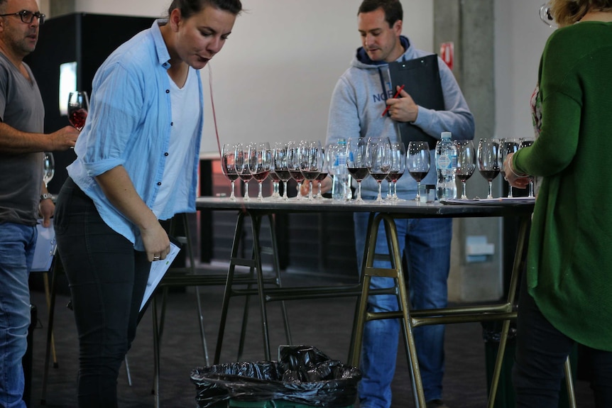 A judge at the Royal Melbourne Wine Awards spits into a bucket.