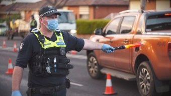 A Victoria Police officer wearing a mask directs traffic.