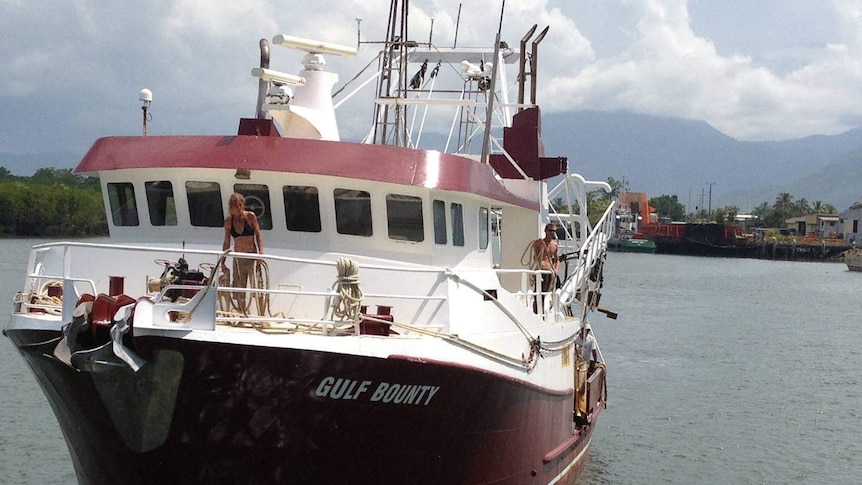 Crew members prepare to throw the ropes as their prawn trawler approaches the wharf in Cairns