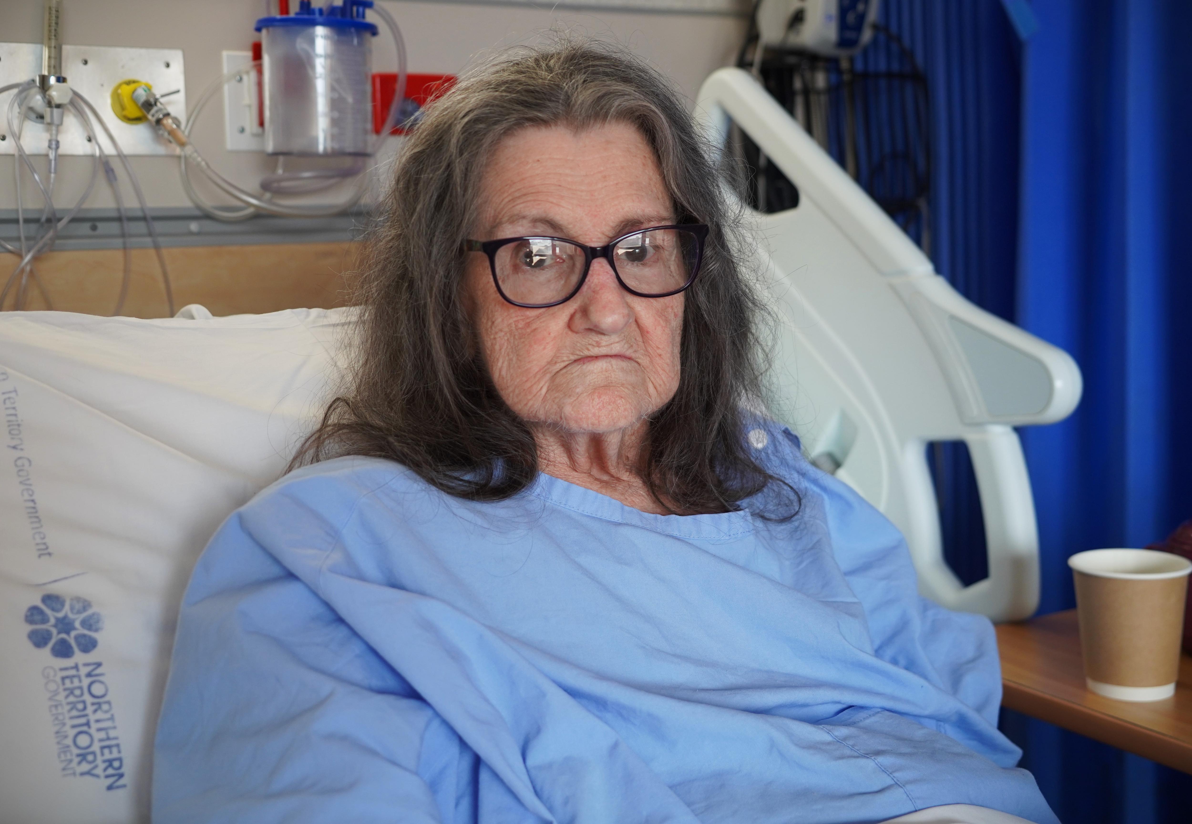 An elderly woman lies in a hospital bed