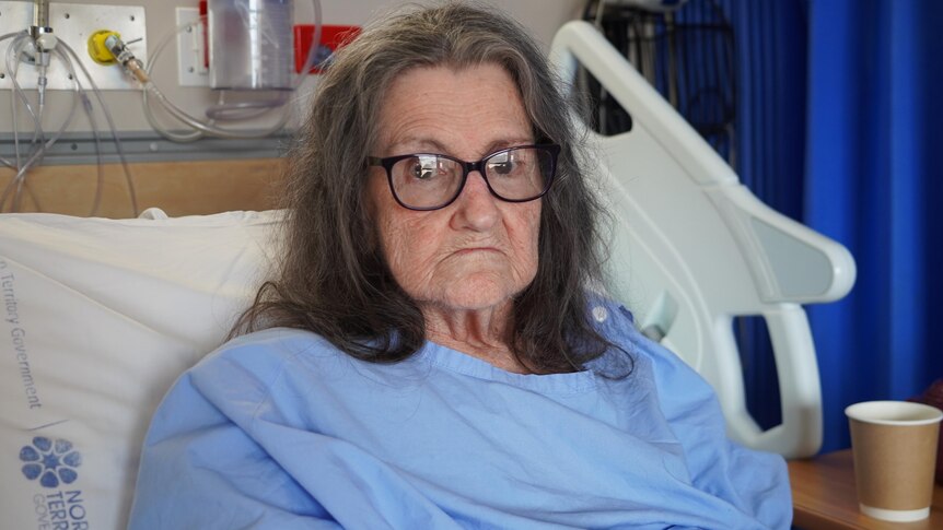 An elderly woman lies in a hospital bed