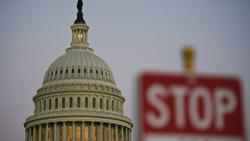 A stop sign is seen at dusk next to the US Congress building