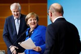 Merkel stands between Seehofer and Schulz on stage