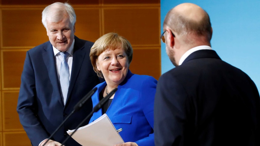 Merkel stands between Seehofer and Schulz on stage
