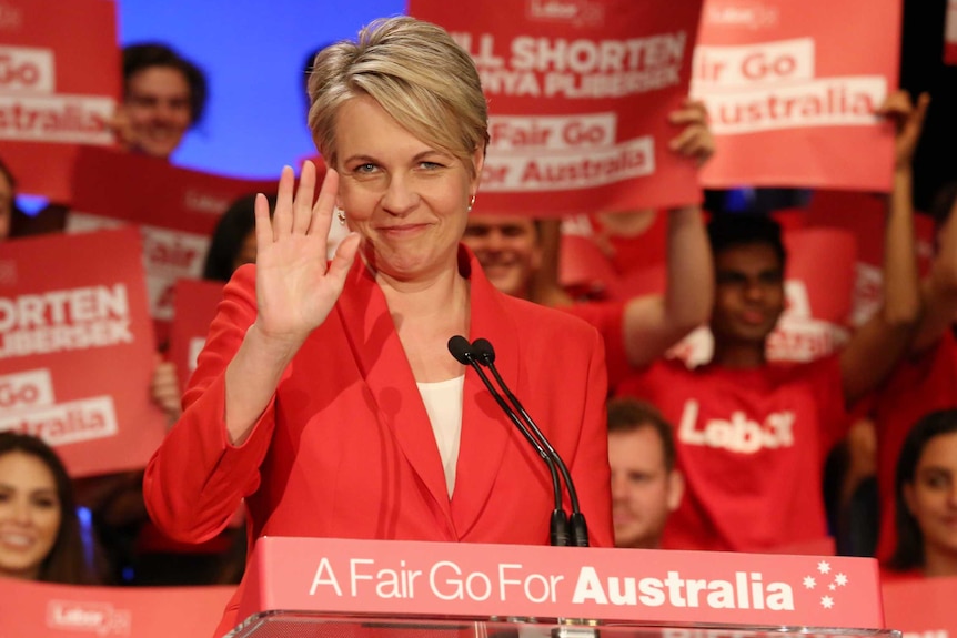 Tanya Plibersek smiles and waves from behind a lectern