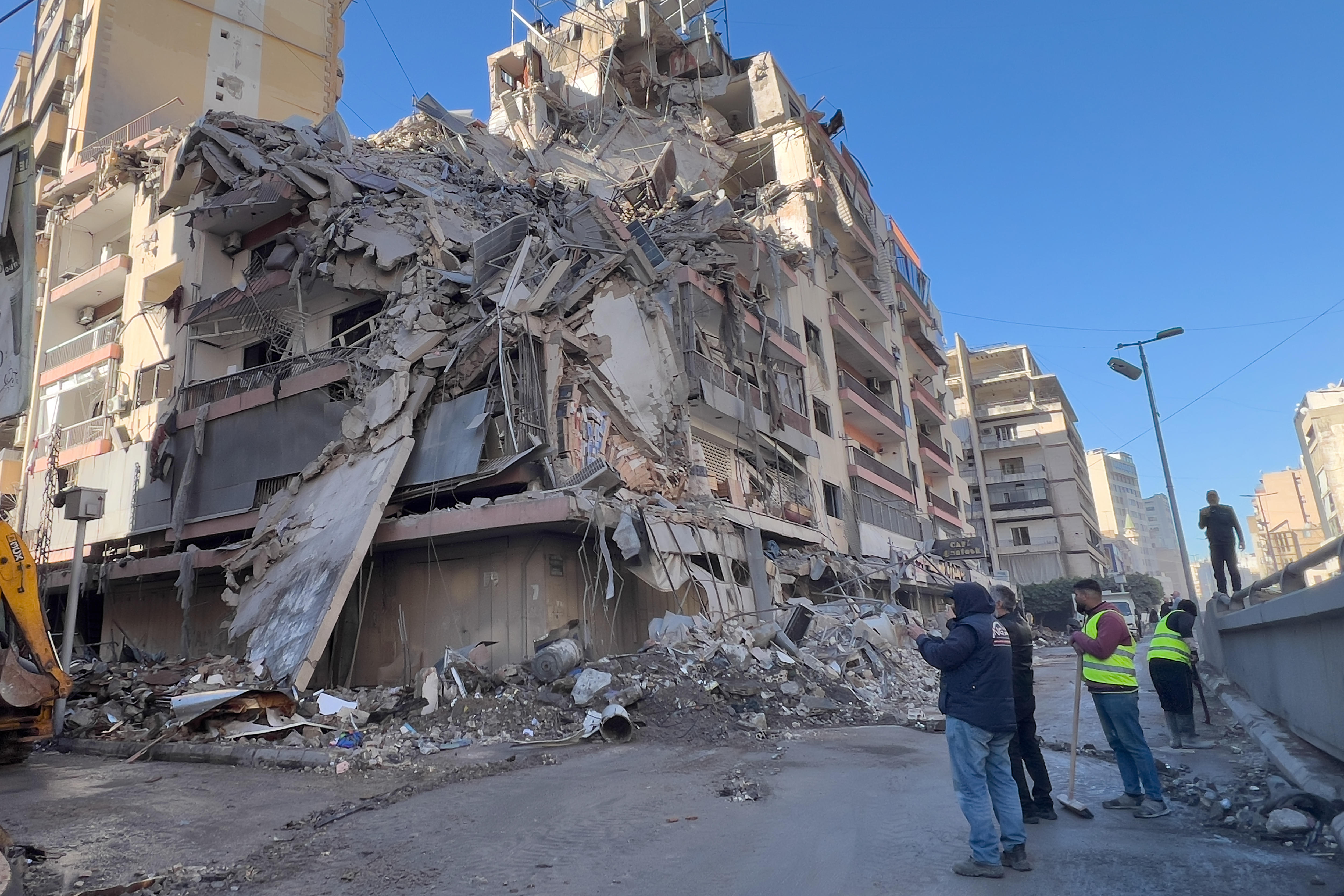 Workers gather in front of a destroyed building that was hit by an Israeli airstrike.