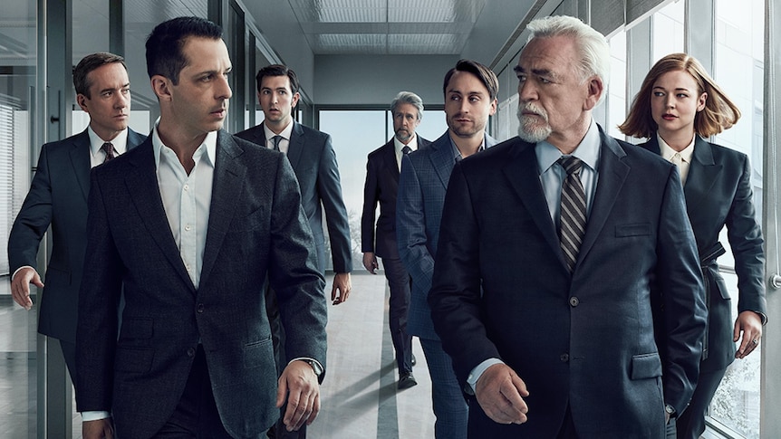 Les personnages de l'émission HBO Succession marchent dans un couloir dans des costumes sombres, se regardant