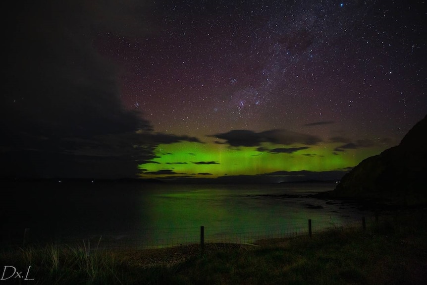 Aurora Australis  is seen in the distance from the coast.