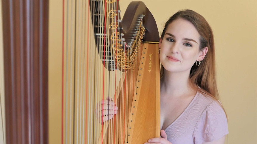 Harpist and Wiradjuri woman Kaela Phillips holds her harp.