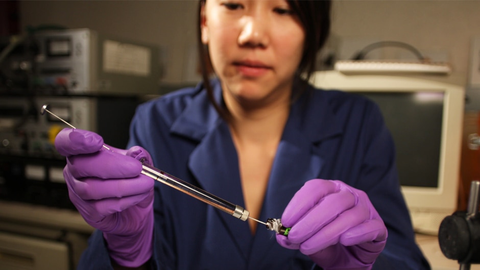 A scientist wearing gloves works in a lab.