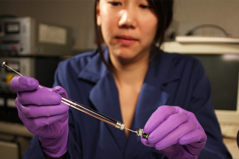A scientist wearing gloves works in a lab.