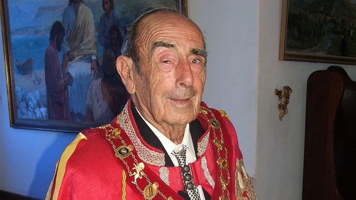 Man in red robes with a gold chain around his neck