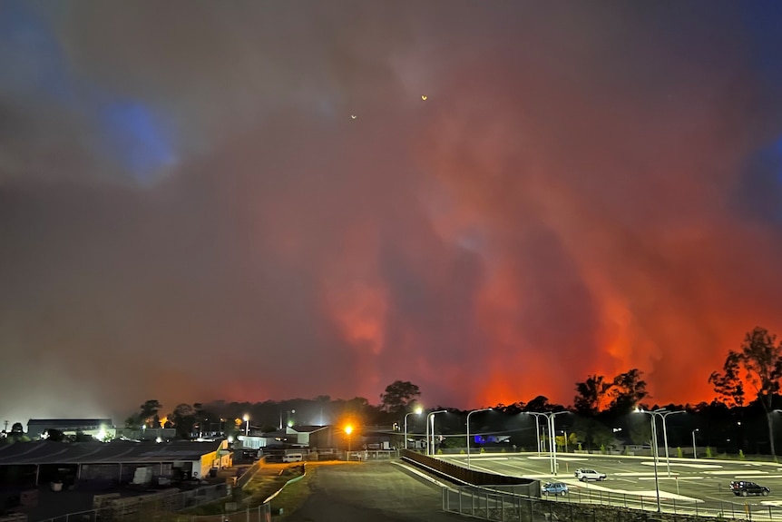 towering flames in background of empty carpark