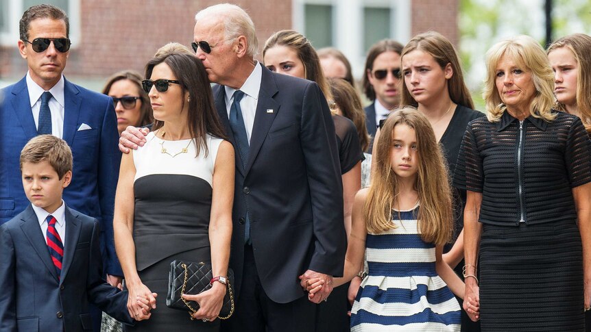 Joe Biden with his arm around Hallie Biden while holding his granddaughter's hand