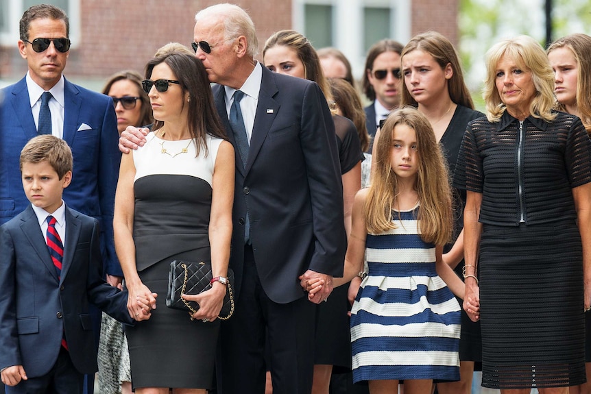 Joe Biden with his arm around Hallie Biden while holding his granddaughter's hand