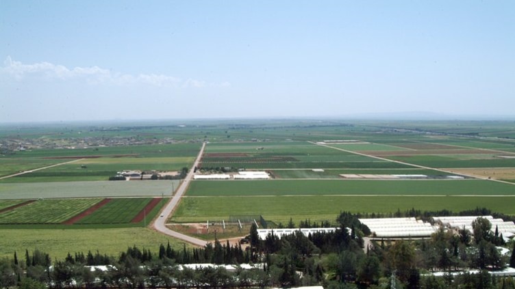 Green fields of crops with neat straight roads and rows of greenhouses and research laboratories pre-war Syria