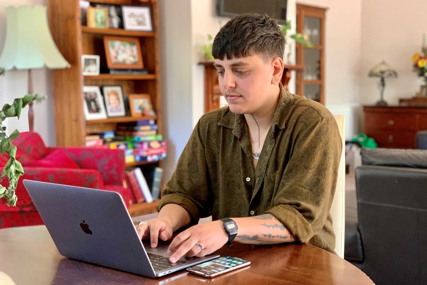 A person sits in front of a computer in a living room in Ballarat