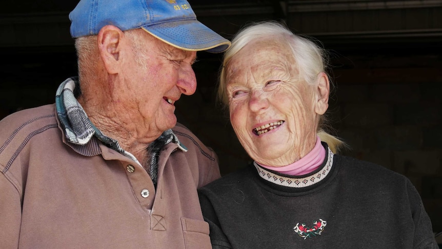 An older man and woman laugh and look fondly at each other