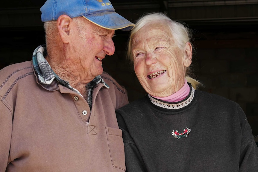 An older man and woman laugh and look fondly at each other