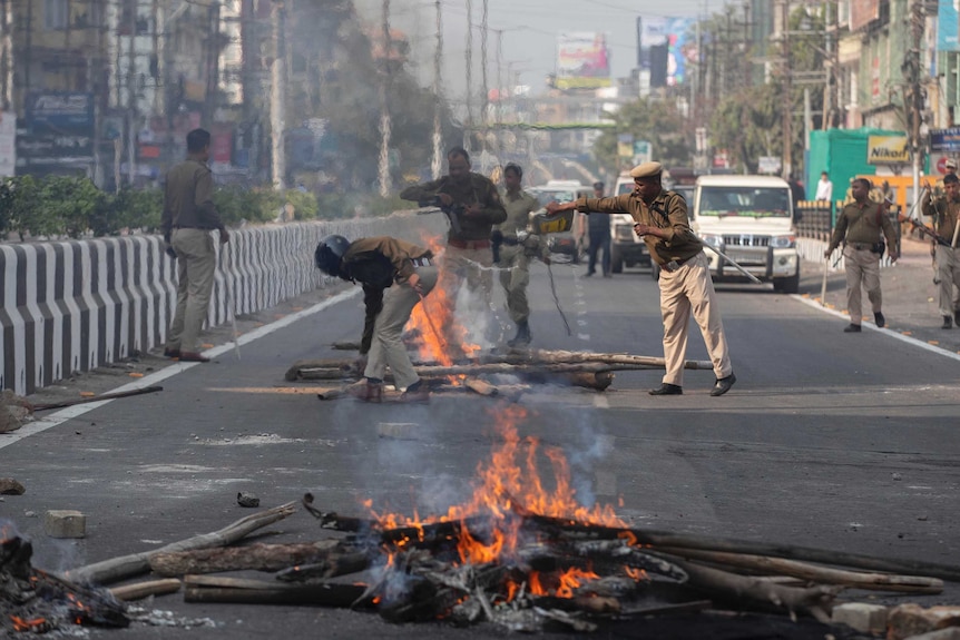 Police douse fires with water in the middle of the street as they try to remove road blocks in India.