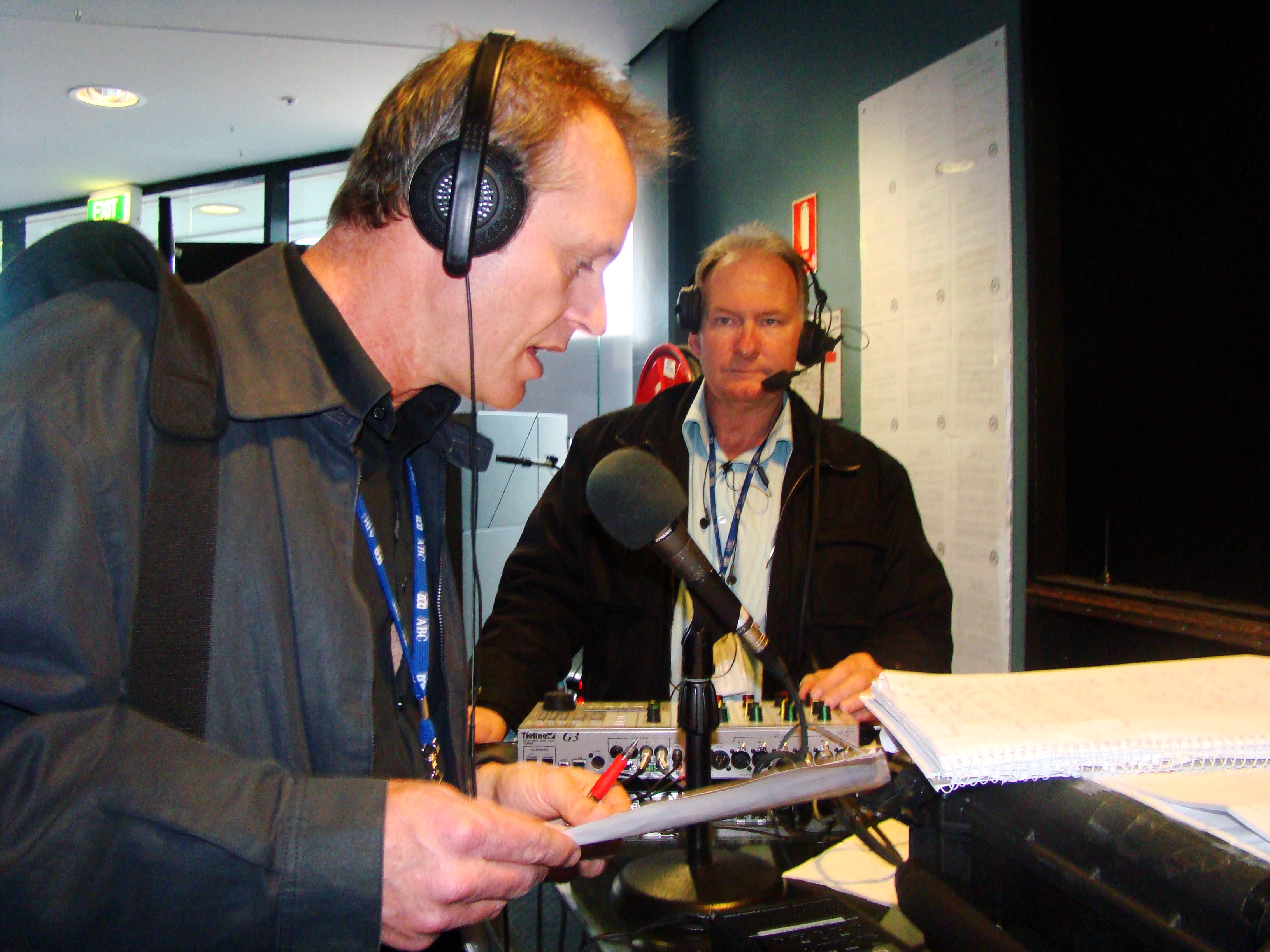 Man with headphones reading book into microphone